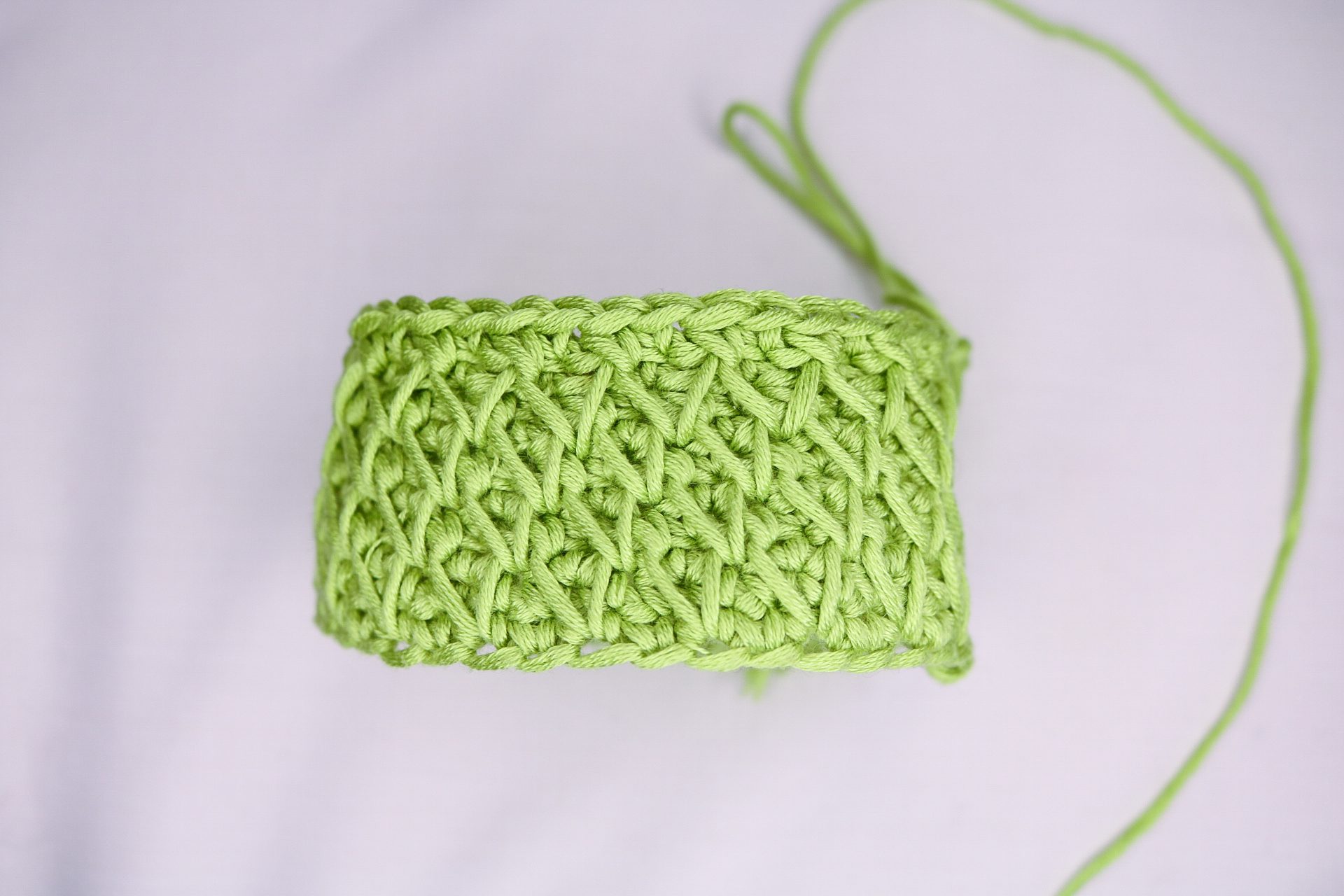 Small tube of bright green crochet worked in honeycomb stitch, showing the raised diamond texture and thick edge