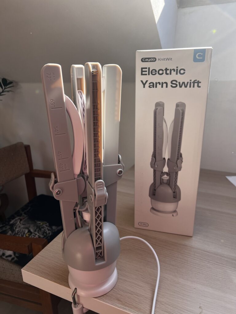 The Caydo Y1 Pro electric yarn swift folded upright beside its box, with the inch scale running along the arm from 40 to 72 inches