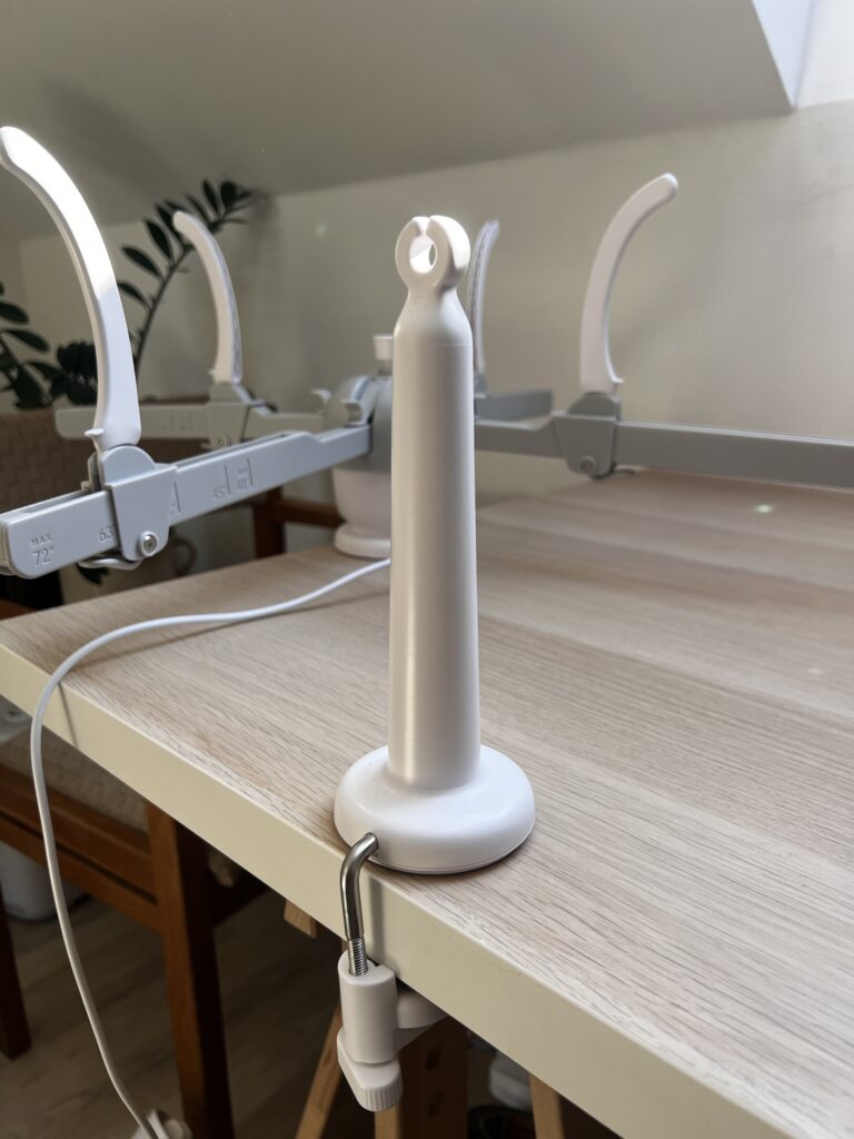 The Caydo Y1 Pro yarn guide clamped to the edge of a table, with the swift arms and their inch scale behind it